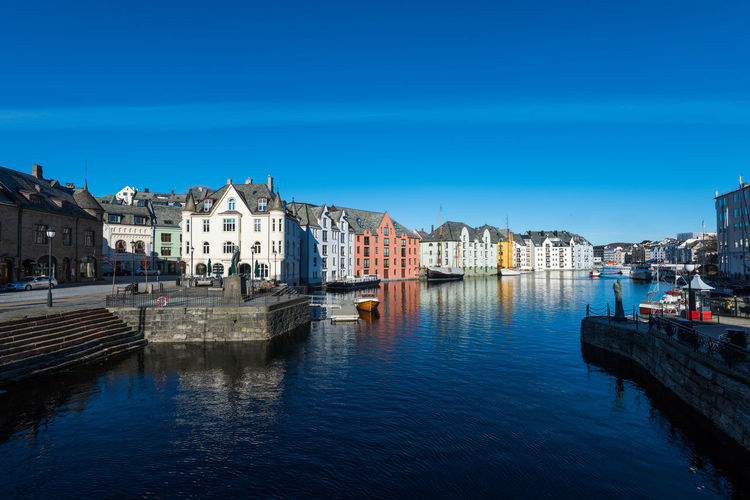 Buildings by river against blue sky