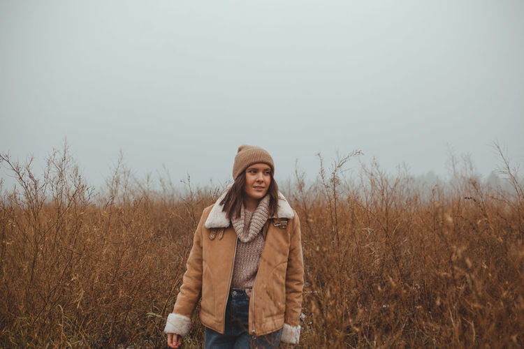 Portrait of mature woman standing on field against sky during winter