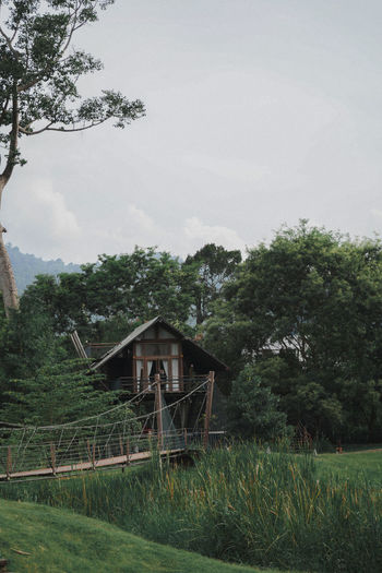 House on field by trees against sky