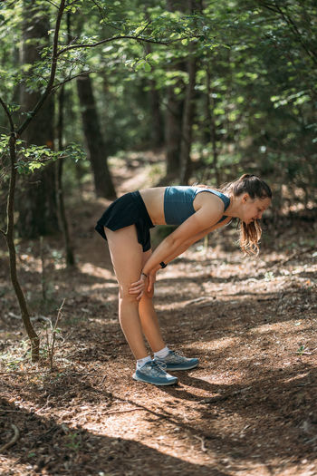 Full length of young woman exercising in forest