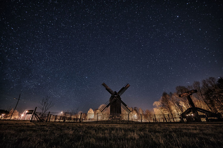 Traditional windmill on field against sky at night