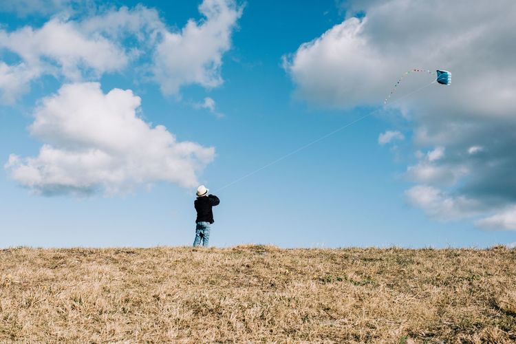 Young boy flying a kite on a hill on a beautiful sunny day