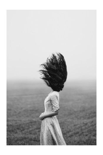 Woman with tousled hair standing on field during foggy weather