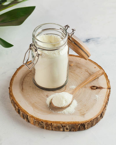 Collagen in the form of a white powder in a glass jar and on a wooden spoon. skin care, 