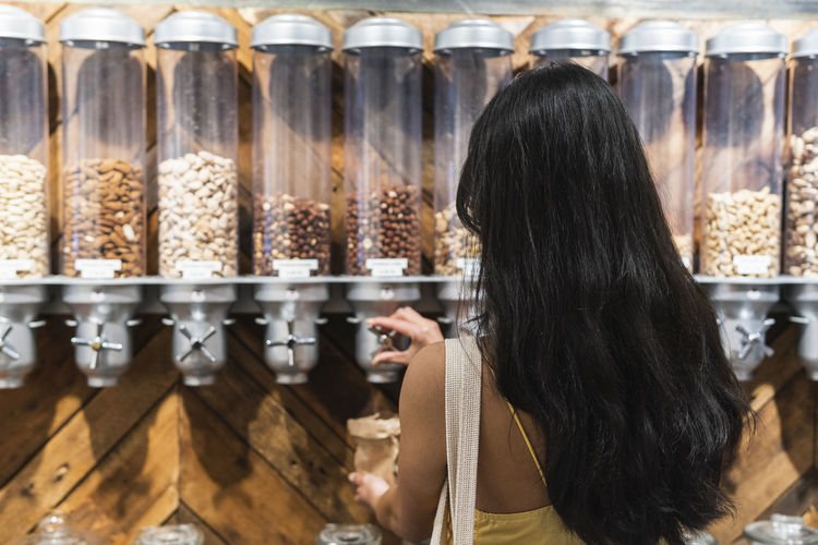 Woman with black hair buying nuts at grocery store