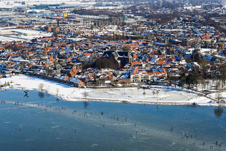 High angle view of illuminated city by sea during winter