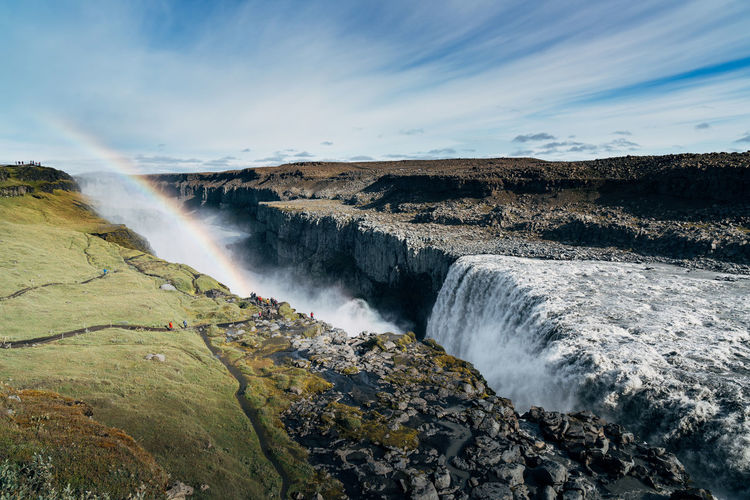 Scenic view of rainbow over waterfall in crater