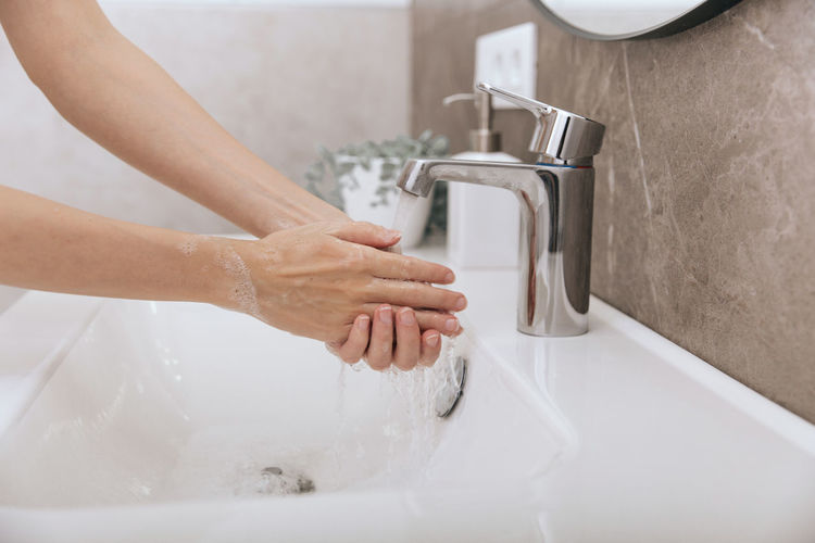 Washing hands under the flowing water tap. hygiene concept hand detail.
