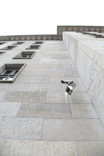 Low angle view of security camera on building against clear sky