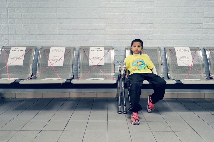 A young boy sitting on the chair alone following the social distancing in a clinic