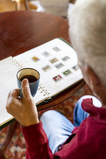 Senior man looking at home at stamp collection