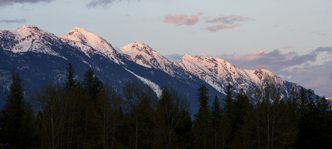 The sun sets on snow covered mountains on a spring day in the coast mountains of british columbia.