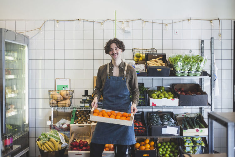 Portrait of smiling male owner with fruit box in store