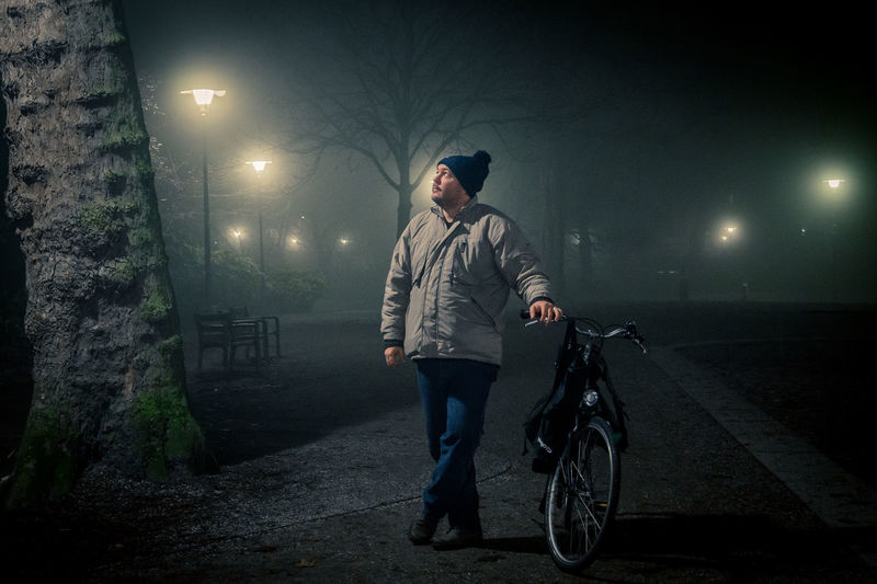 Man standing with bicycle at night