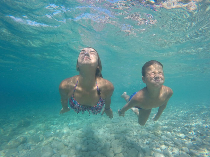 Young woman and boy holding breath underwater