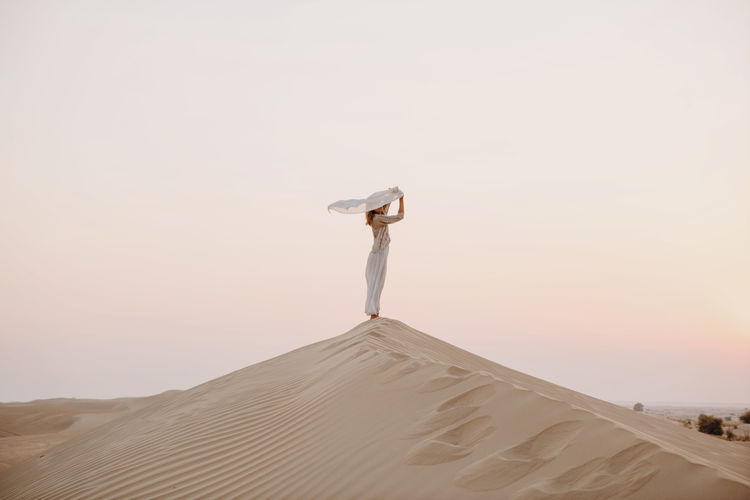 Woman holding scarf in the sand dune in desert