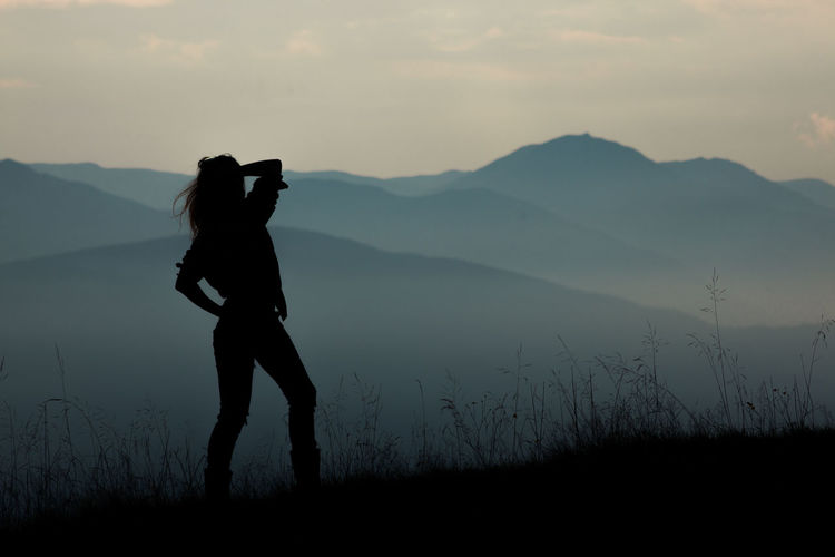 Silhouette woman standing on mountain against sky during sunset
