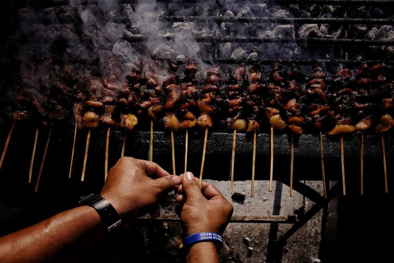 Midsection of man preparing food on barbecue grill