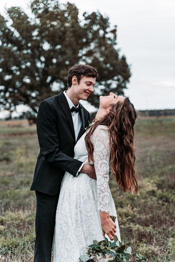 Newlywed couple romancing while standing on land