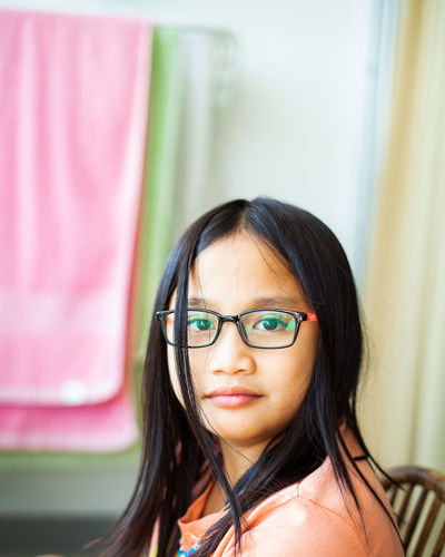 Portrait of young little asian girl age 9 wearing glasses years old in natural light at home.