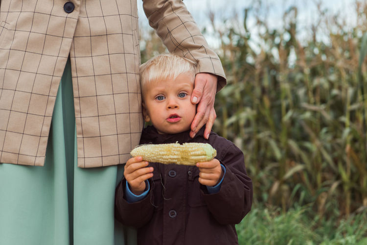 Family walking in corn field at autumn, mom hug son