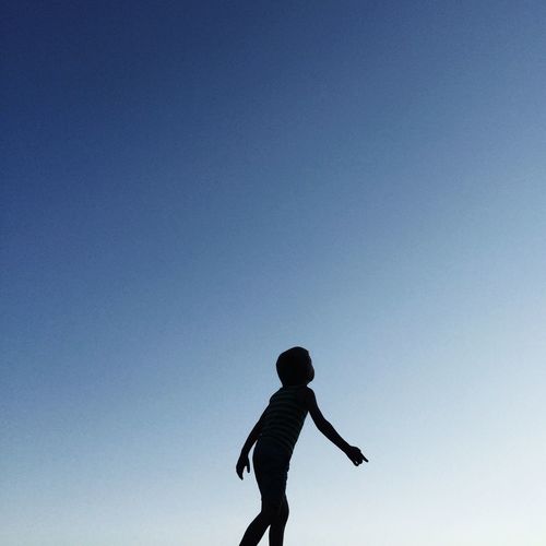 Low angle view of boy standing against cloudy sky