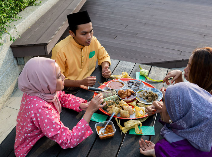 Muslim family enjoys variety of traditional cuisines on circular tray on black table, end of ramadan