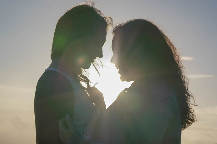 Side view of lesbians against sky during sunset