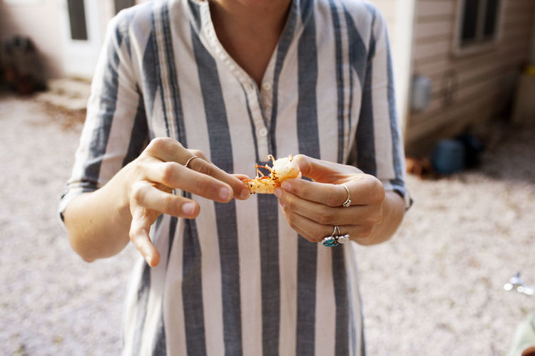 Midsection of woman holding prawn while standing in yard