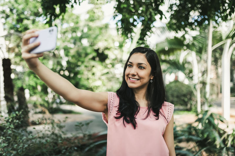 Portrait of smiling young woman using mobile phone outdoors