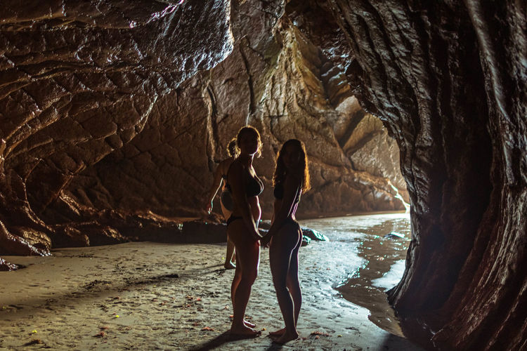 Rear view of woman and girl standing in cave