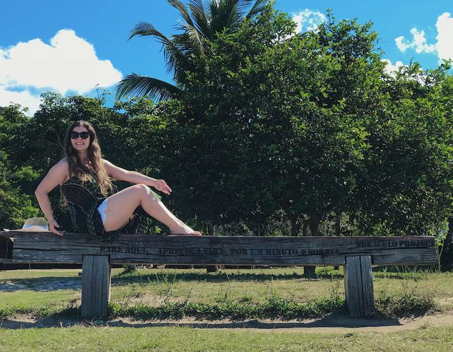 Portrait of woman sitting on railing against trees