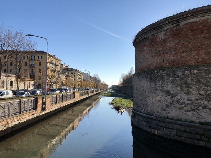 Canal amidst buildings against clear sky