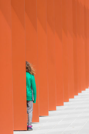 Rear view of woman standing against orange wall