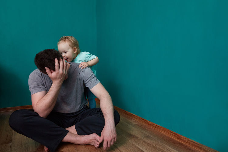 Full length of father with daughter against wall