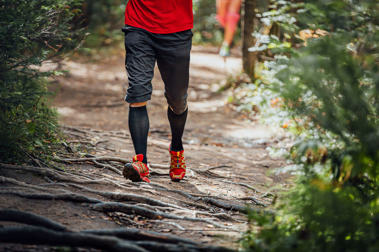 Male runner in compression calf sleeve run forest trail