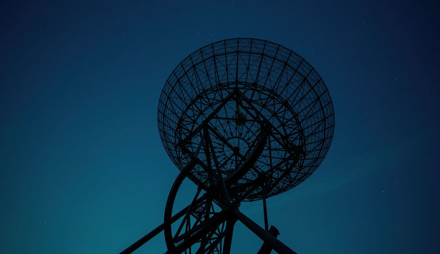 Low angle view of communications tower against clear blue night sky