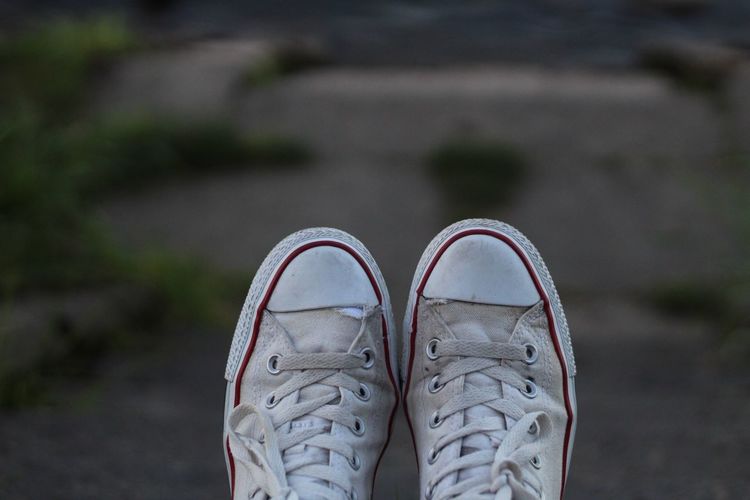 Low section of person wearing canvas shoes standing outdoors