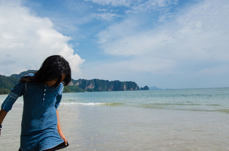 Teenage girl standing against sea at beach