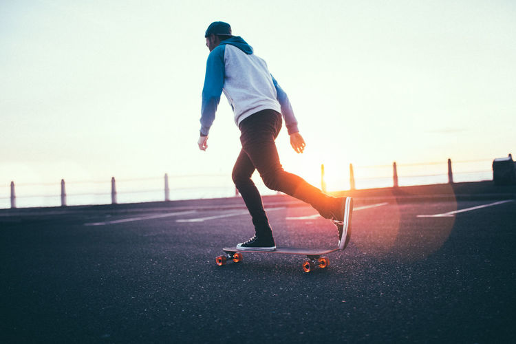 Full length of man skateboarding on road against sky