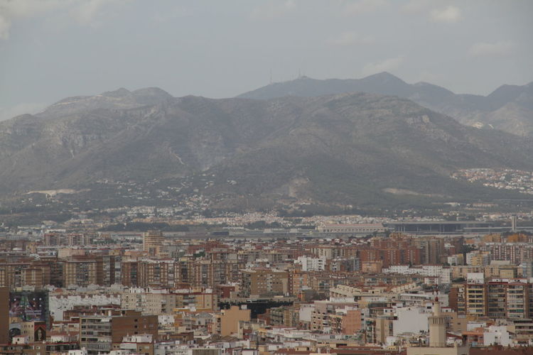 Aerial view of cityscape and mountains against sky