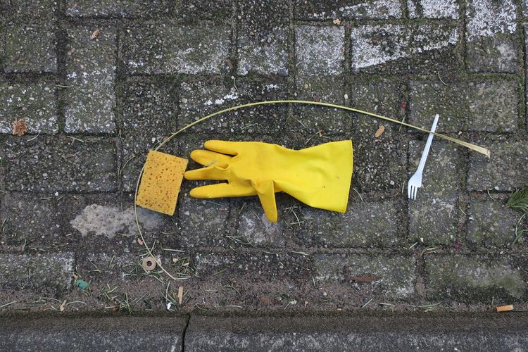 Directly above shot of protective glove and sponge on footpath