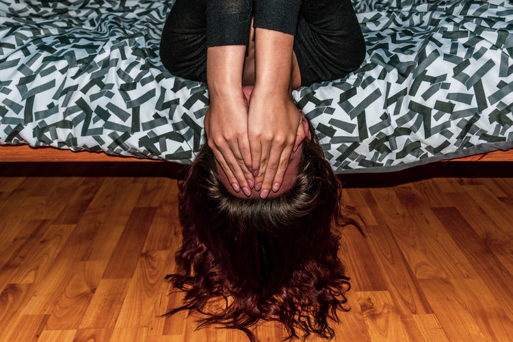 Upside down image of woman lying down on bed at home