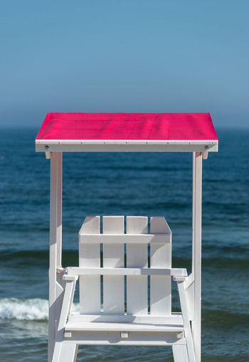 White lifeguard chair visible from the back with a pink visor against the background beautiful sea 