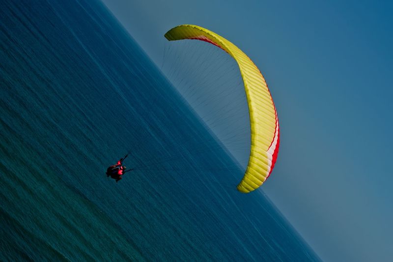 High angle view of person paragliding over sea against clear blue sky