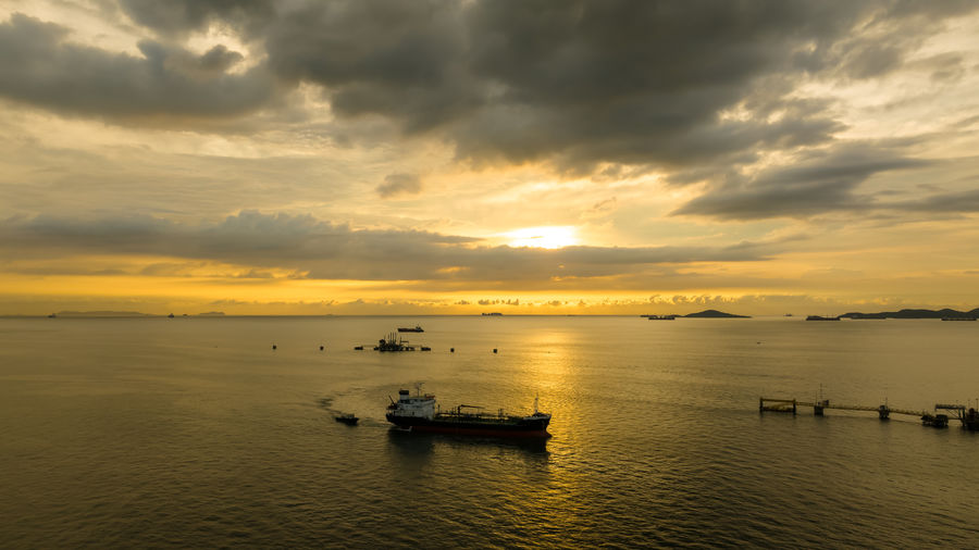 Seascape the sunset and oil tanker ship sailing in sea and the sunset background aerial view 