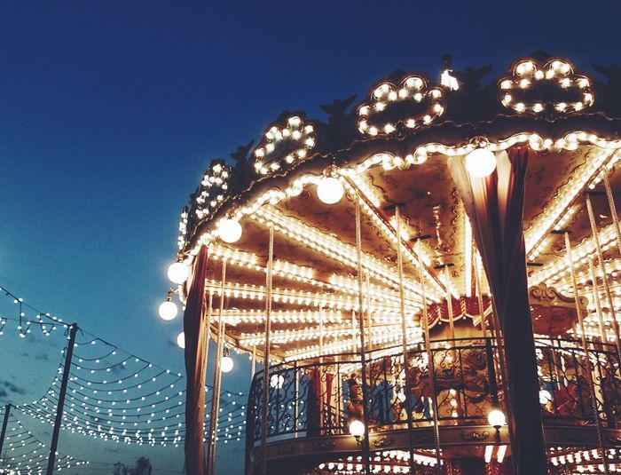 Low angle view of illuminated carousel against sky at night