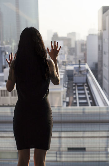 Rear view of woman with arms outstretched against cityscape