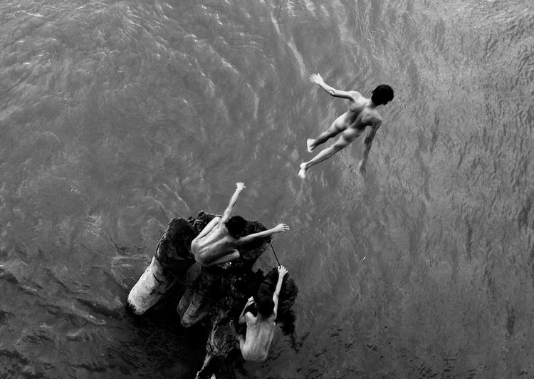 High angle view of boy jumping from rock into sea