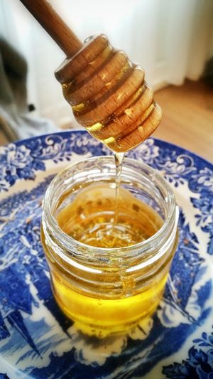 Honey dripping off from dipper into jar